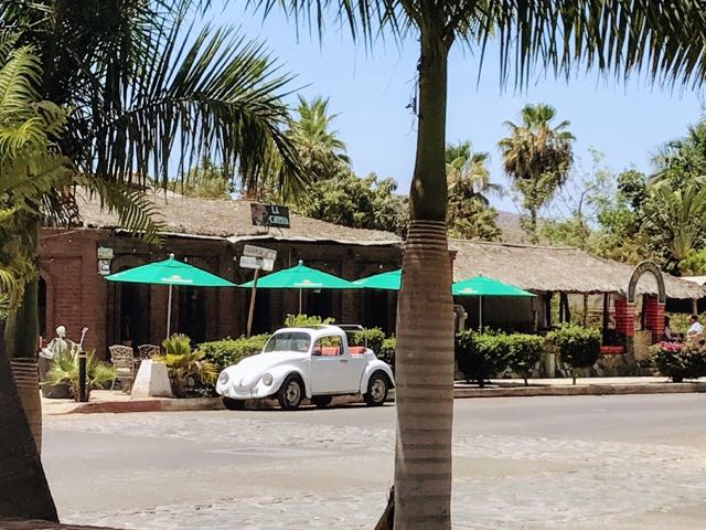 Convertible Beetle car parked outside a restaurant with green umbrellas in Baja California