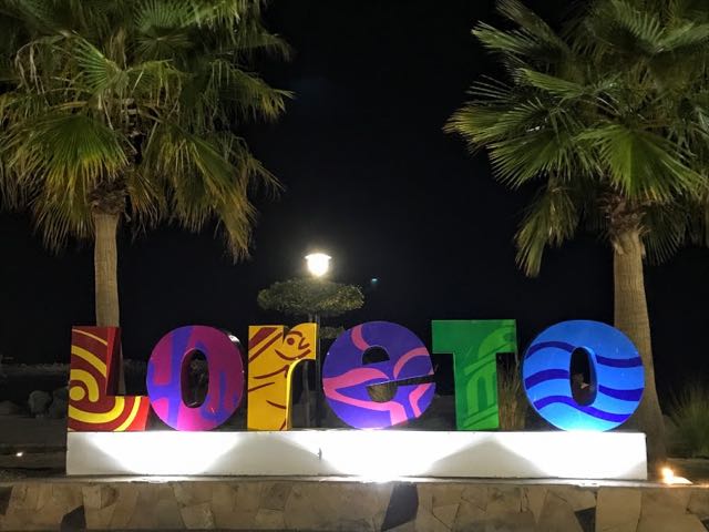 Bright coloured Loreto sign with palm trees at night