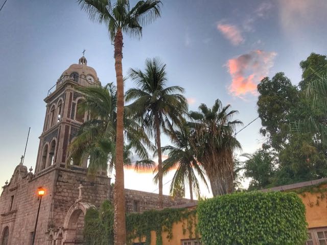 Loreto Mission church at dusk with palm trees